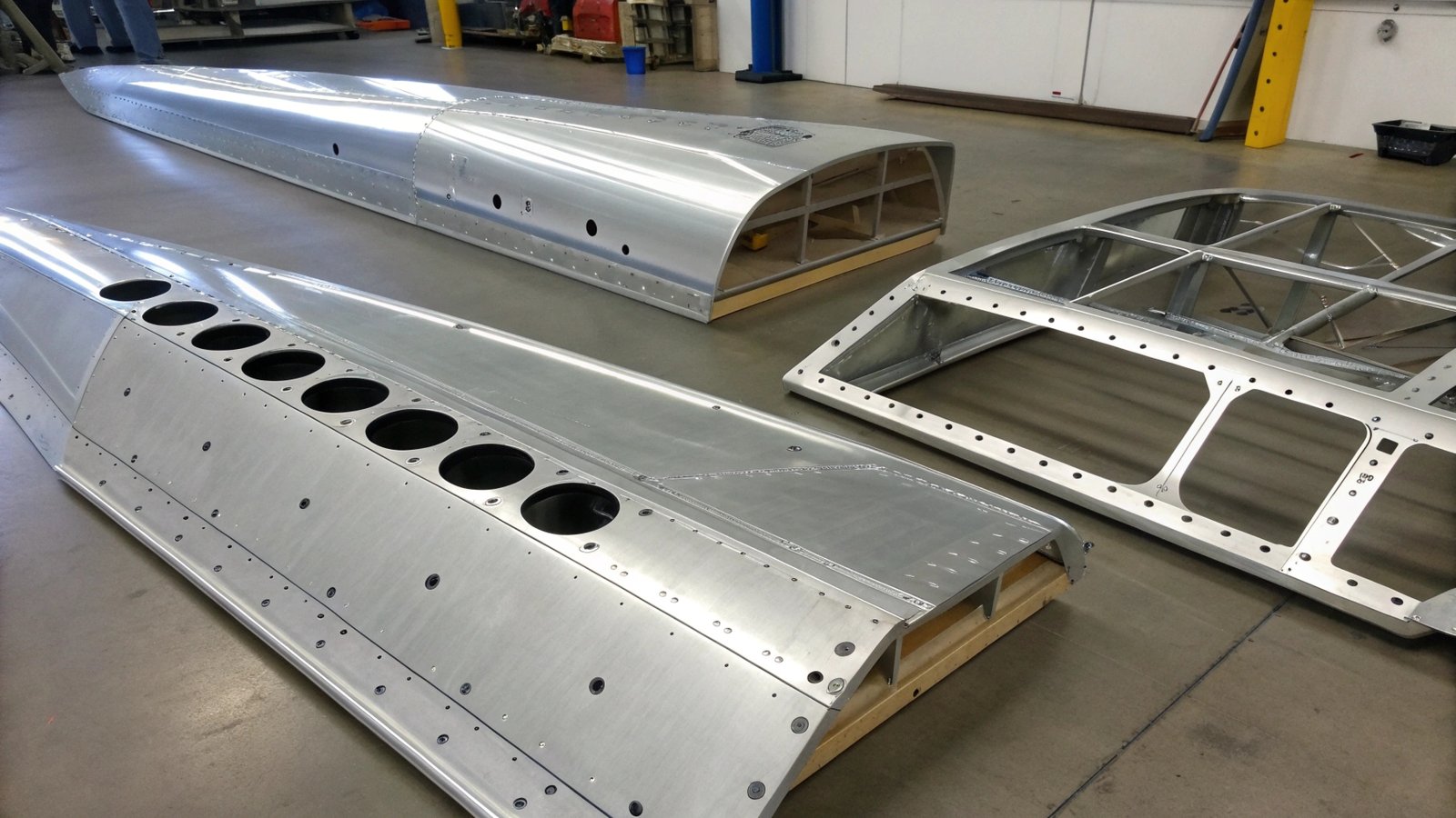 An intricate network of aluminum fuel lines and a hydraulic fluid tank inside an aircraft maintenance bay.